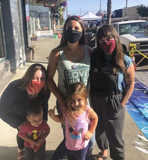 Women with masks and children posing for a picture