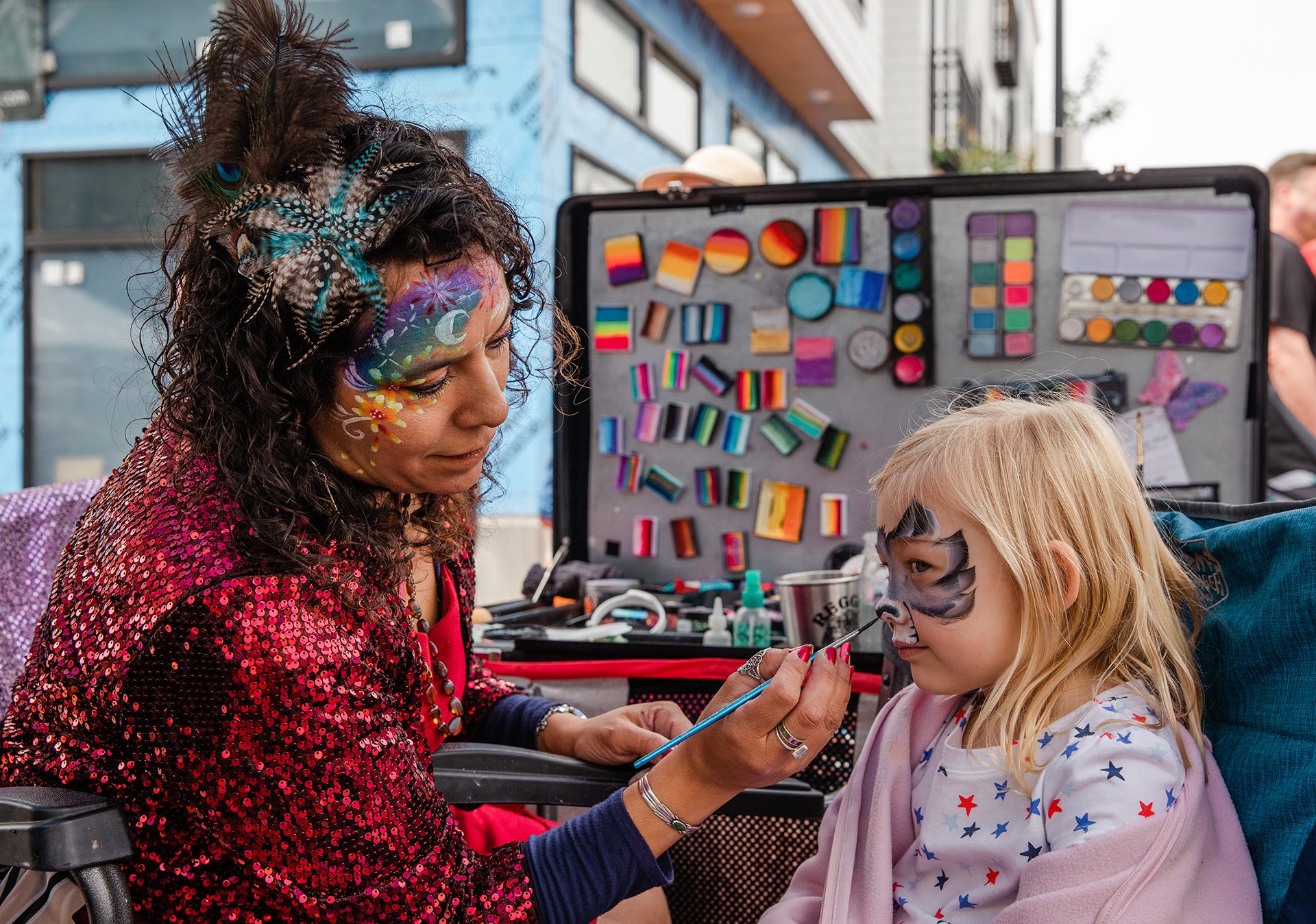 Woman painting a little girl's face with face paint