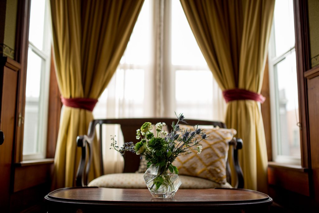 flowers in a vase in a little sitting room with yellow curtains