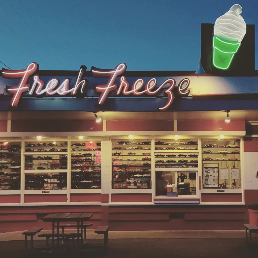 Neon "Fresh Freeze" sign on top of diner at night